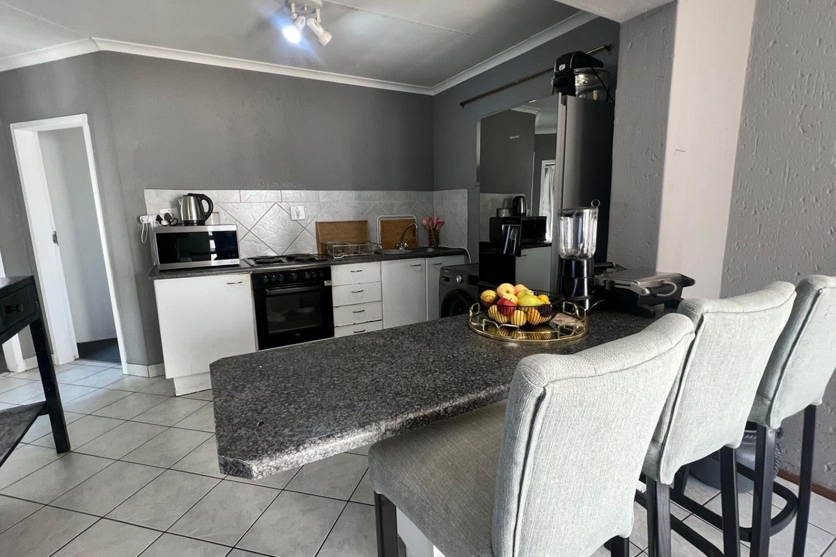 Compact kitchen featuring a breakfast bar, built-in oven, hob, and tiled flooring, offering a functional layout for daily meal preparation.