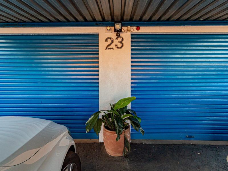 A double garage featuring blue roller shutter doors and exterior security lighting.