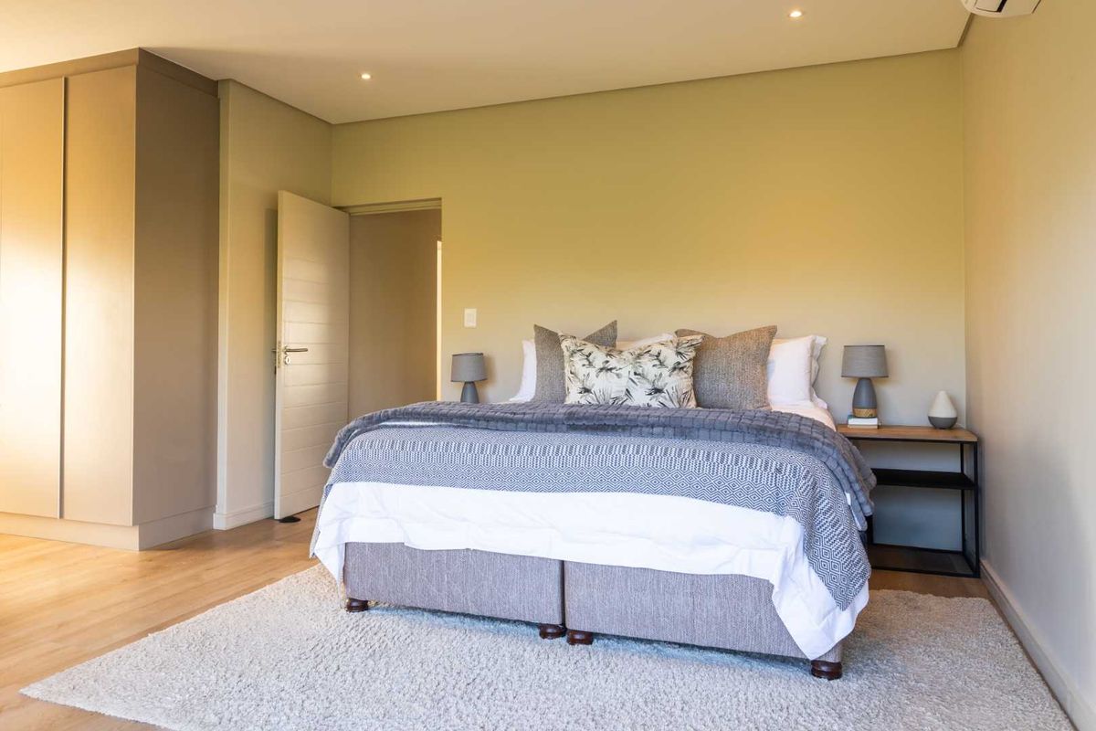 A well-maintained bedroom featuring neutral walls, laminate flooring, built-in cupboards, and recessed downlighting.