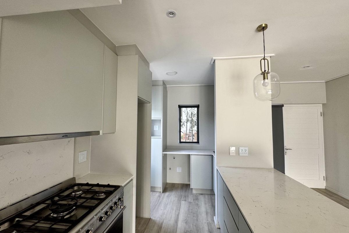 Modern kitchen featuring stone countertops, gas cooktop, integrated cabinetry, and a functional layout with a breakfast bar and adjacent scullery area.