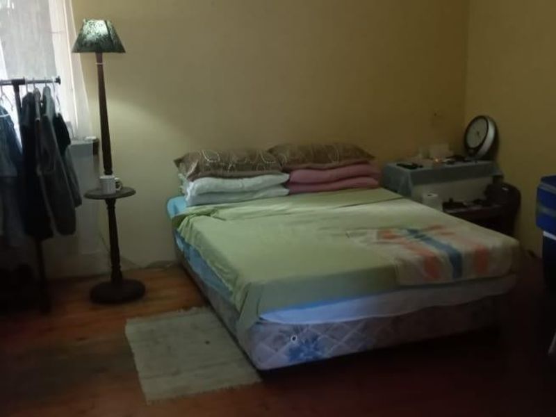A bedroom featuring timber flooring and natural light, currently utilized as a living space.