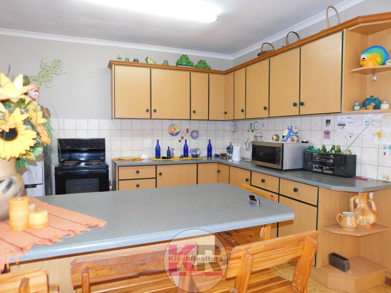 A functional kitchen featuring laminate cabinetry, tiled backsplash, and a built-in breakfast nook, offering a practical layout with standard fixed appliances.