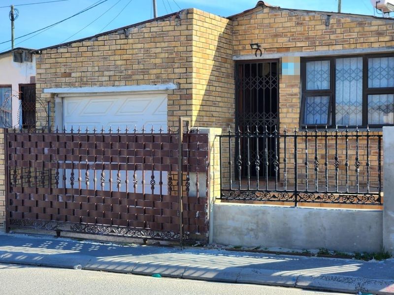 Front elevation of a face brick house featuring a garage, security gate, and wrought iron perimeter fencing.