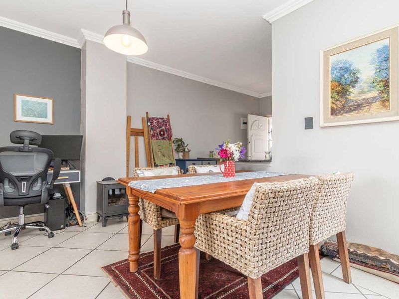 Open plan living and dining area featuring neutral wall tones, tiled flooring, and decorative coving, providing a versatile space for daily living.