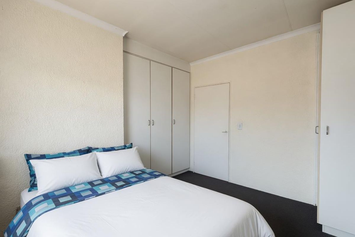A bedroom featuring built-in cupboards, textured wall finishes, and dark carpeting.