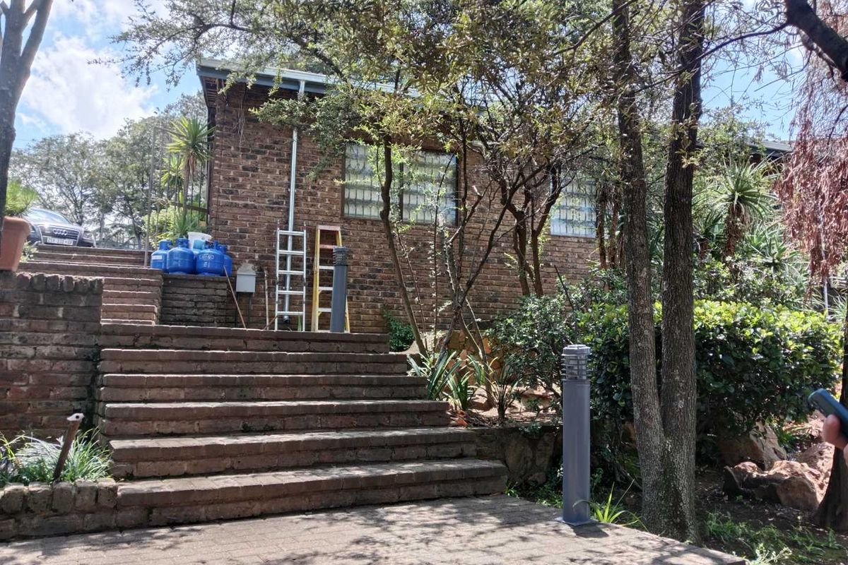 A view of the property's exterior featuring brick facade, stone staircase, and landscaped garden area with integrated pathway lighting.