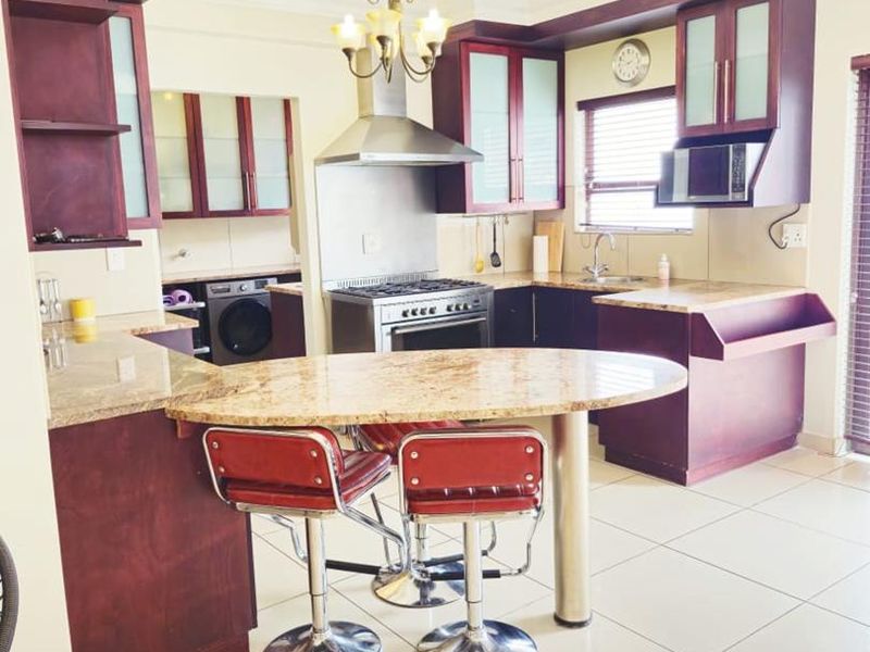 Spacious kitchen featuring dark wood cabinetry, granite countertops, a stainless steel gas stove, and a breakfast bar island.