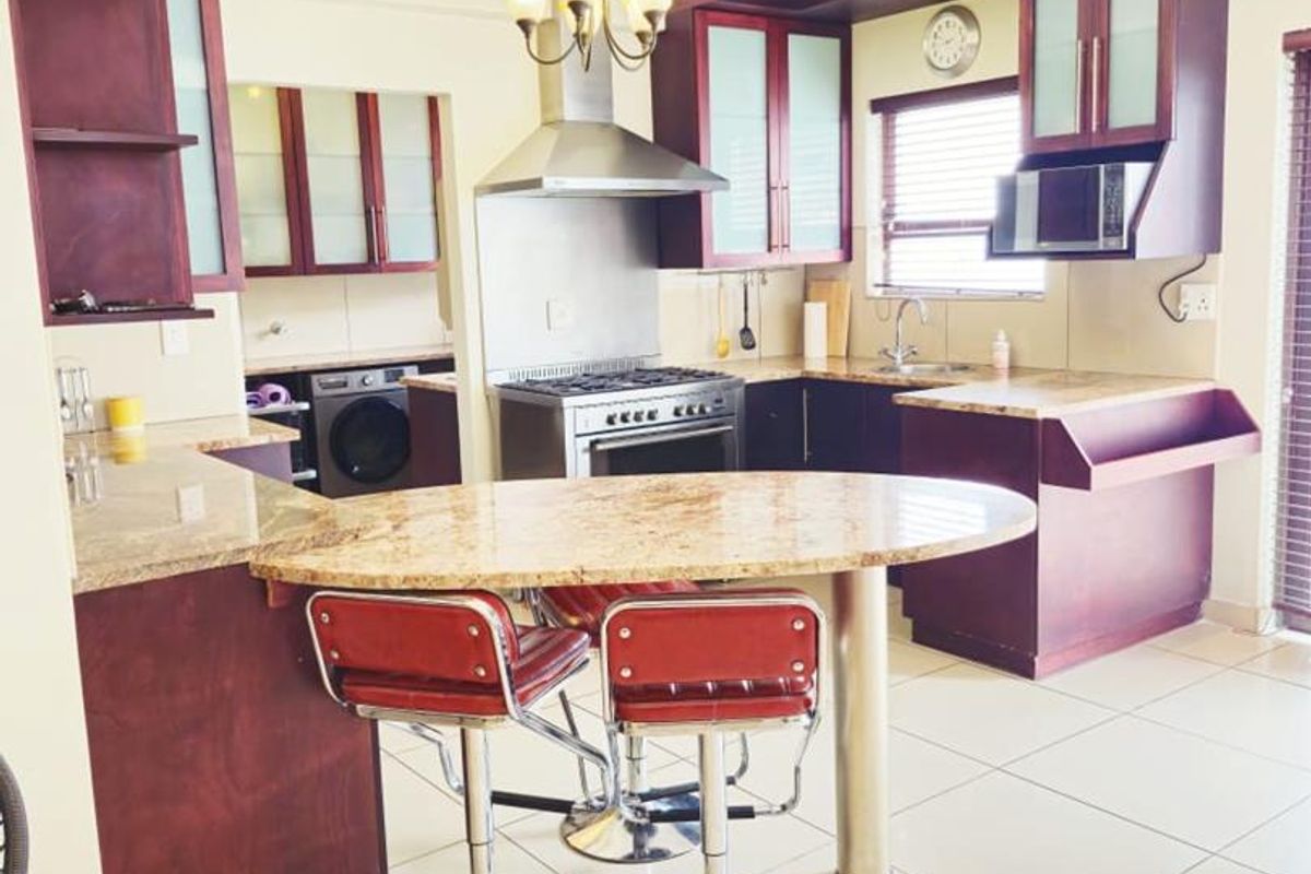 Spacious kitchen featuring dark wood cabinetry, granite countertops, a stainless steel gas stove, and a breakfast bar island.