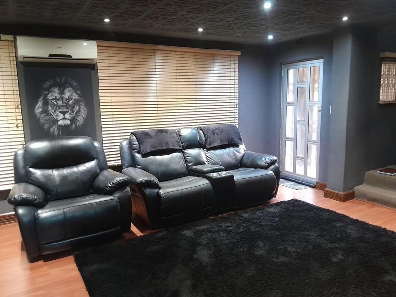 A modern living room featuring dark walls, a textured ceiling, laminate flooring, and a split-system air conditioner.