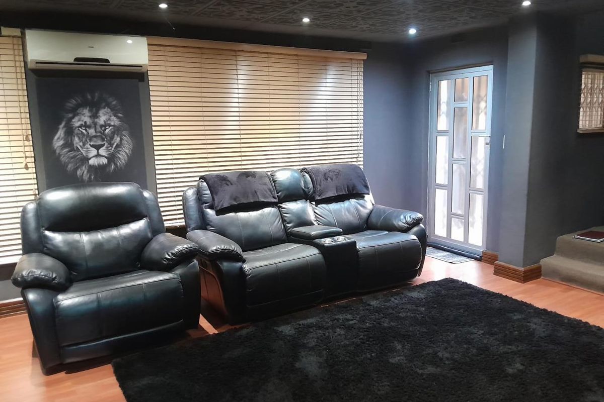 A modern living room featuring dark walls, a textured ceiling, laminate flooring, and a split-system air conditioner.