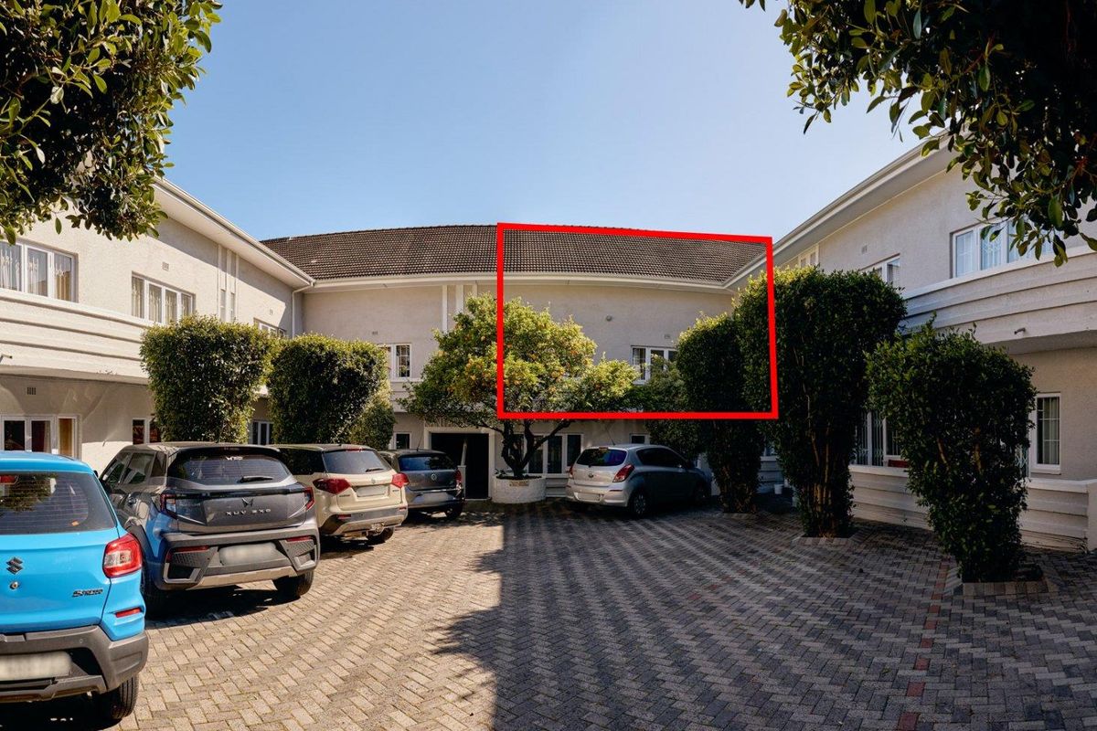 Exterior view of the apartment complex courtyard featuring a paved driveway, mature landscaping, and tiled roof structure.