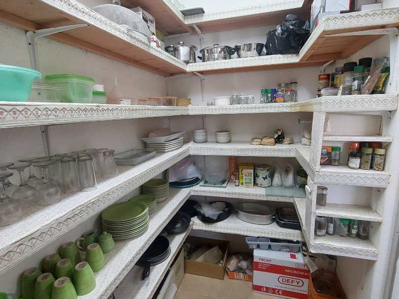 A functional walk-in pantry or scullery area featuring extensive built-in shelving for organized storage and durable tiled flooring.