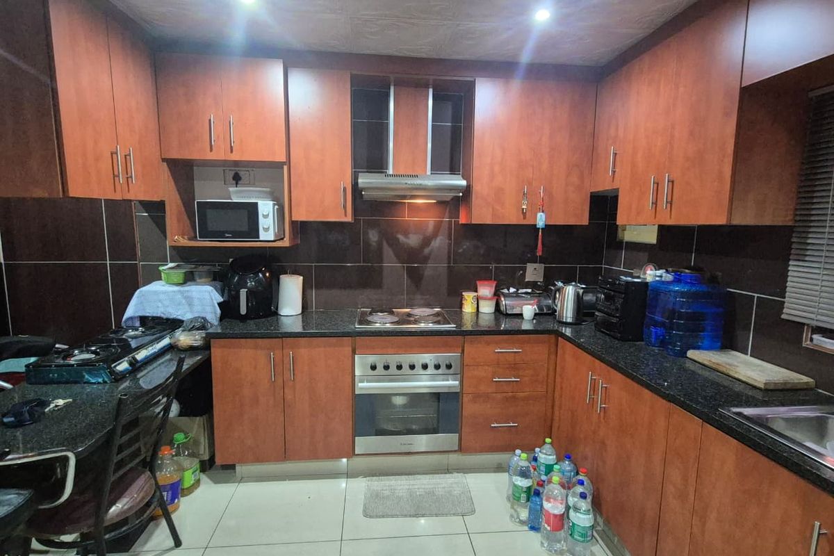 A functional kitchen featuring wood-finish cabinetry, granite countertops, a built-in oven with hob, and a tiled backsplash.
