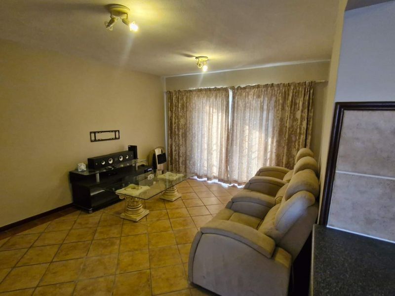 A living room featuring tiled flooring and sliding glass doors that provide access to the exterior, offering a functional and neutral living space.