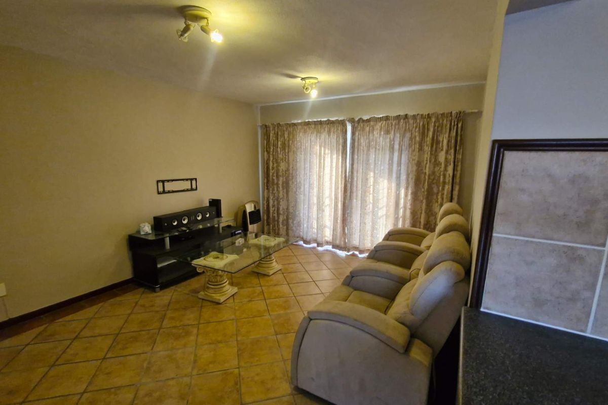 A living room featuring tiled flooring and sliding glass doors that provide access to the exterior, offering a functional and neutral living space.