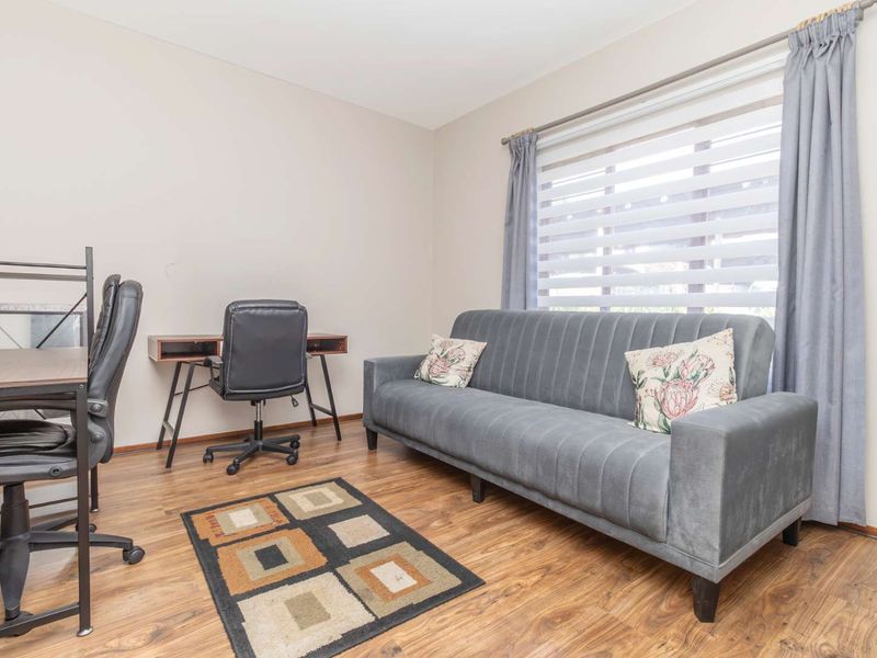 A functional home office space featuring durable laminate flooring and adjustable window blinds, providing a neutral and versatile work environment.