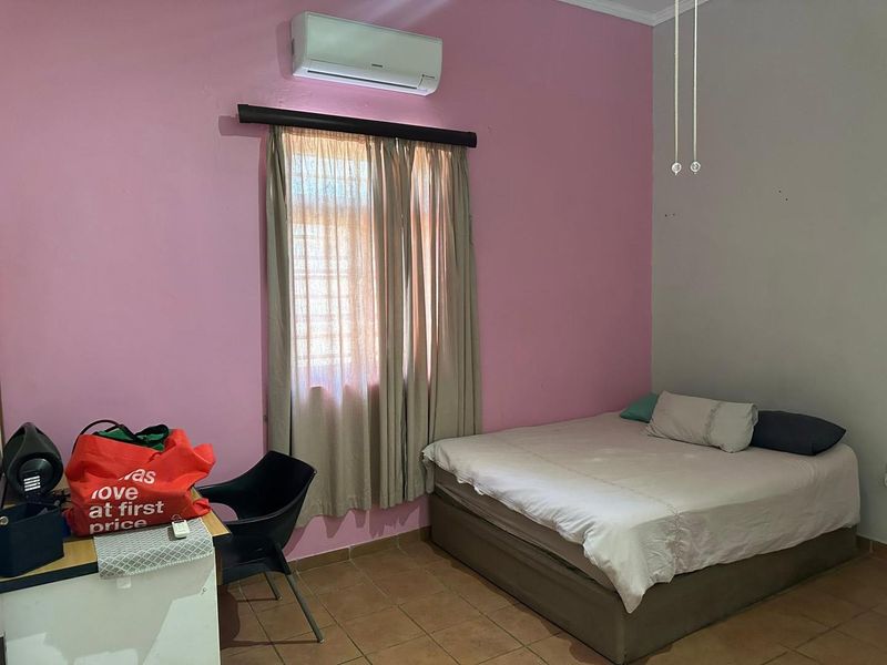 A bedroom featuring tiled flooring and a wall-mounted split-system air conditioner unit.