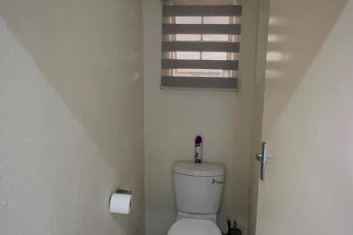 A compact, functional guest toilet featuring tiled flooring and a standard white toilet suite.