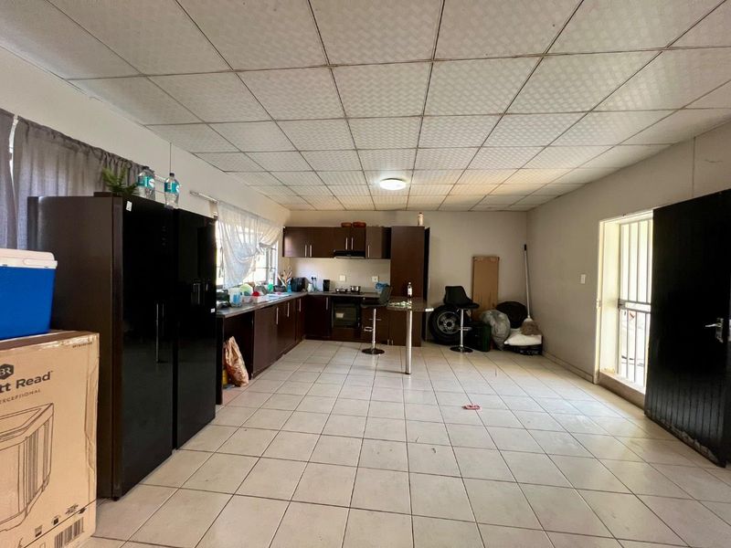 A spacious kitchen featuring dark built-in cabinetry, integrated appliances, tiled flooring, and a drop ceiling, offering significant potential for modernization and layout optimization.
