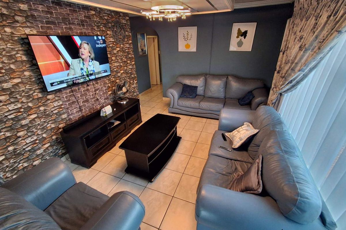 A comfortable living room featuring a stone veneer accent wall, tiled flooring, and a decorative ceiling fixture, creating a cozy and inviting atmosphere.