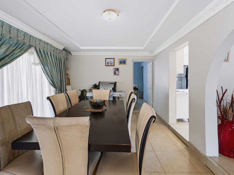 Dining room featuring tiled flooring, decorative ceiling cornices, and an arched entryway leading to the kitchen area.