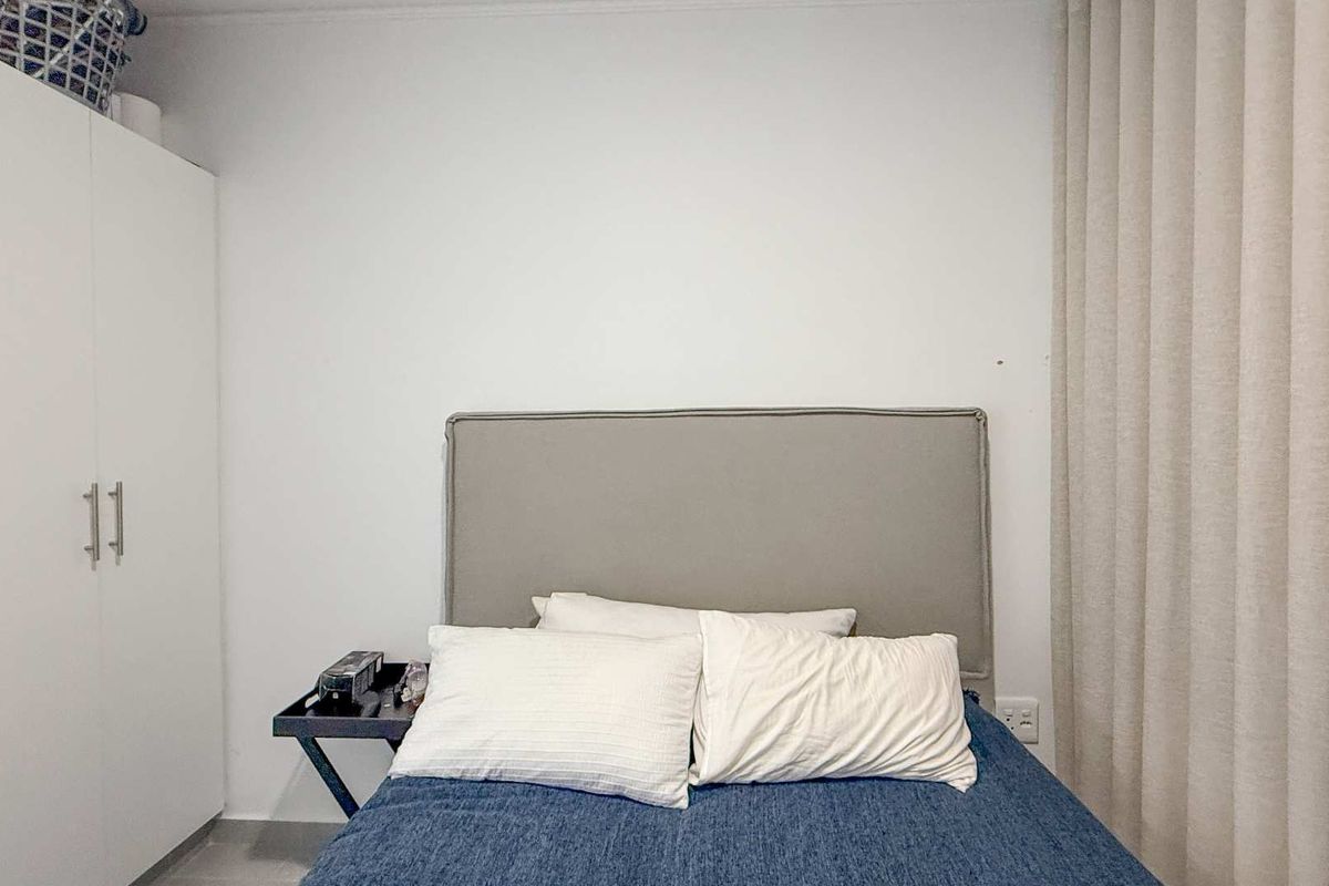 A bedroom featuring a built-in wardrobe and floor-to-ceiling curtains, providing a functional and neutral space.