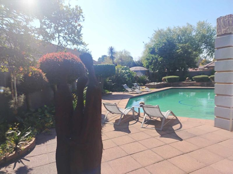 Outdoor pool area featuring a paved deck and established garden surroundings, providing a private space for relaxation and recreation.