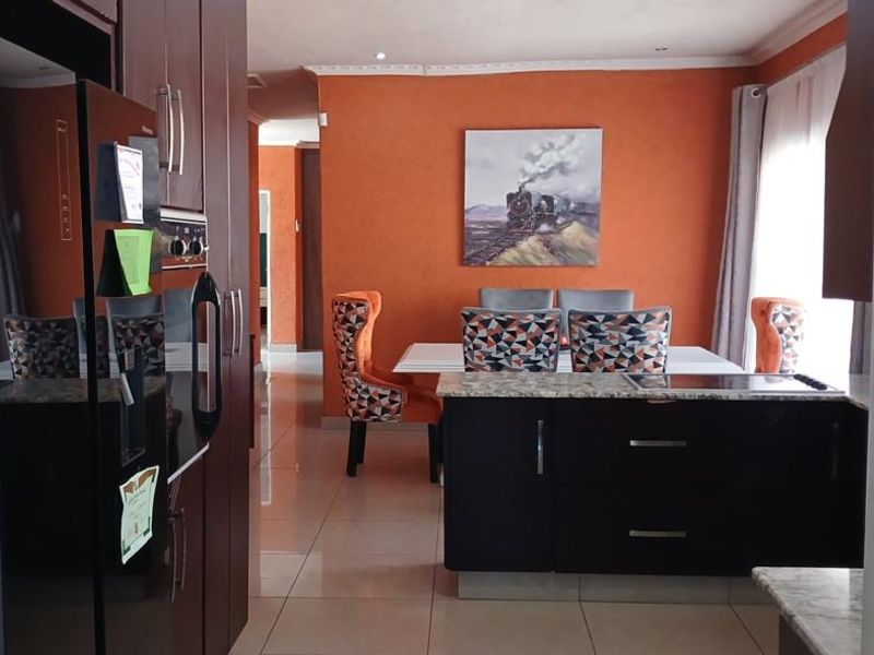 Open plan kitchen and dining area featuring dark wood cabinetry, granite countertops, and polished ceramic floor tiles.