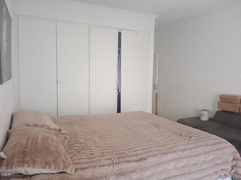A functional bedroom featuring built-in cupboards with white doors, providing ample storage space.