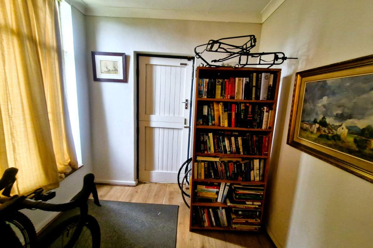 A functional room featuring wood-look flooring, a classic panelled door, and large windows allowing for natural light.