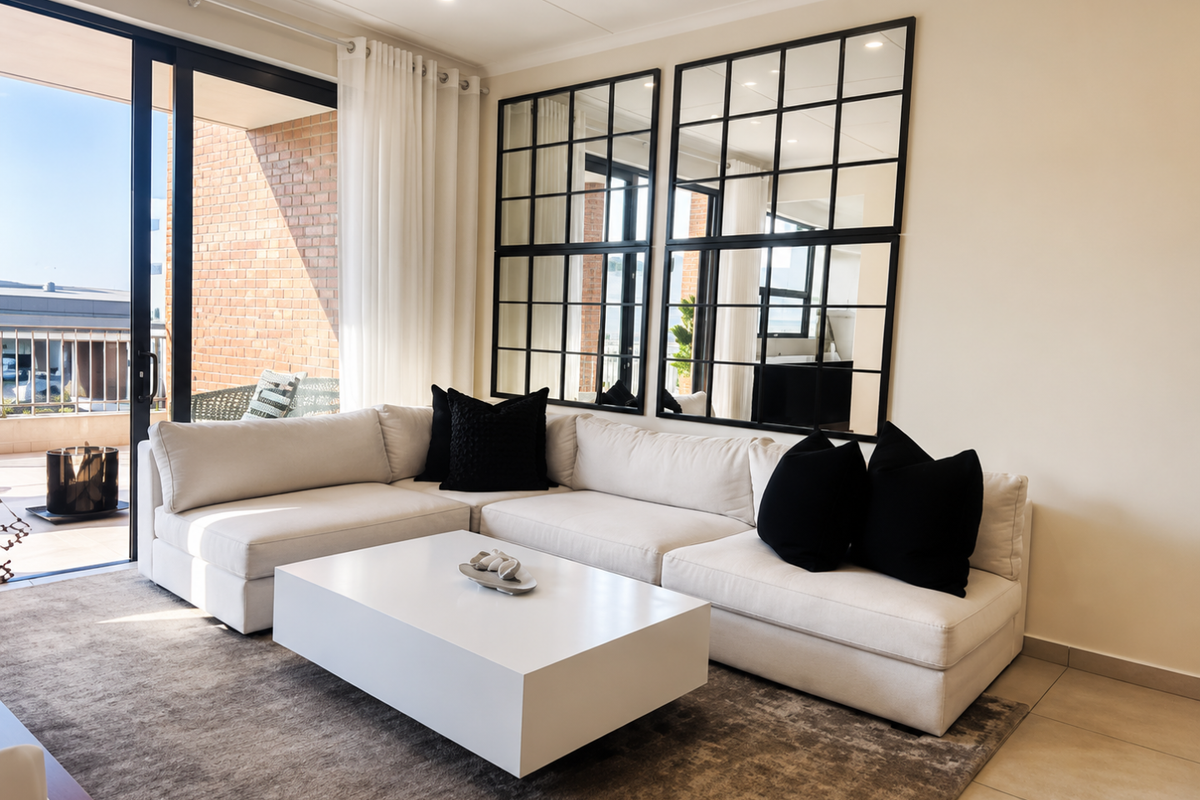 A bright and modern living room featuring large window mirrors, recessed lighting, and a sliding glass door leading to an outdoor balcony area.