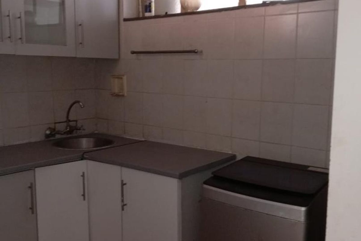A functional laundry area featuring built-in cabinetry, a stainless steel sink, tiled backsplash, and tiled flooring.