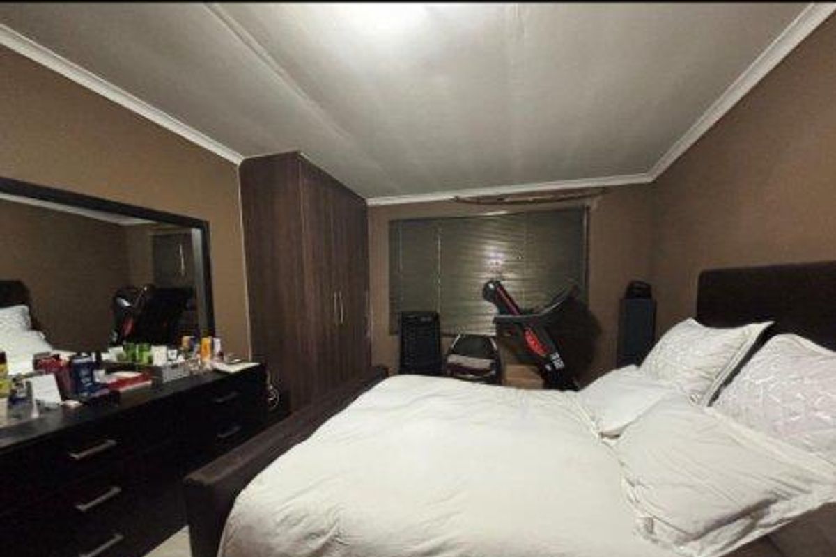 A spacious bedroom featuring built-in wooden cabinetry and neutral wall tones, providing a functional and comfortable sleeping area.