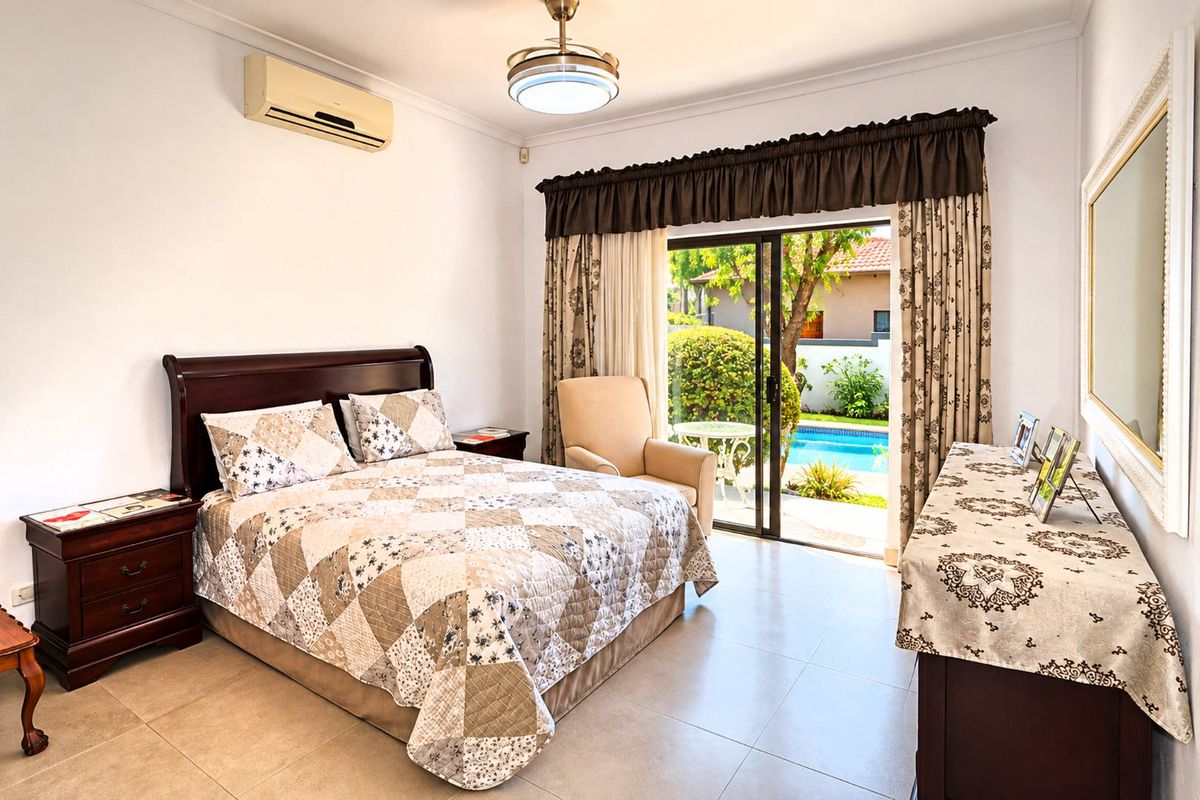 Spacious bedroom featuring tiled flooring, a split-system air conditioner, and direct access to the pool area through sliding glass doors.