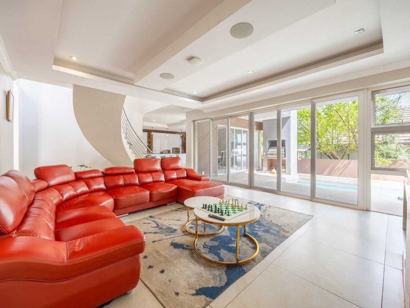 Spacious living room featuring recessed ceiling lighting, tiled floors, and large sliding glass doors that provide seamless access to the outdoor patio and pool area.