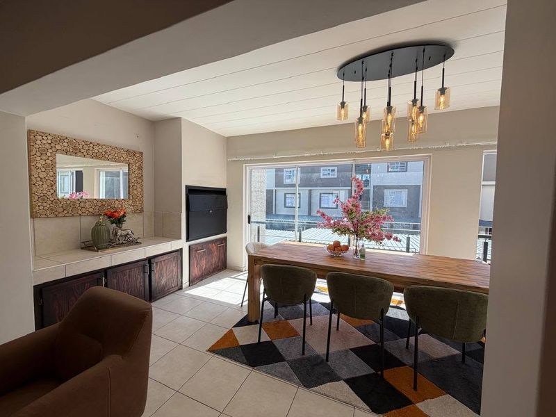 Open plan living and dining area featuring tiled floors, built-in cabinetry, a fireplace, and large sliding doors leading to a balcony.