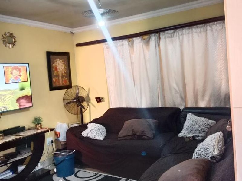 A living room featuring tiled flooring and ceiling cornice, currently requiring cosmetic updates to the wall finishes and ceiling.