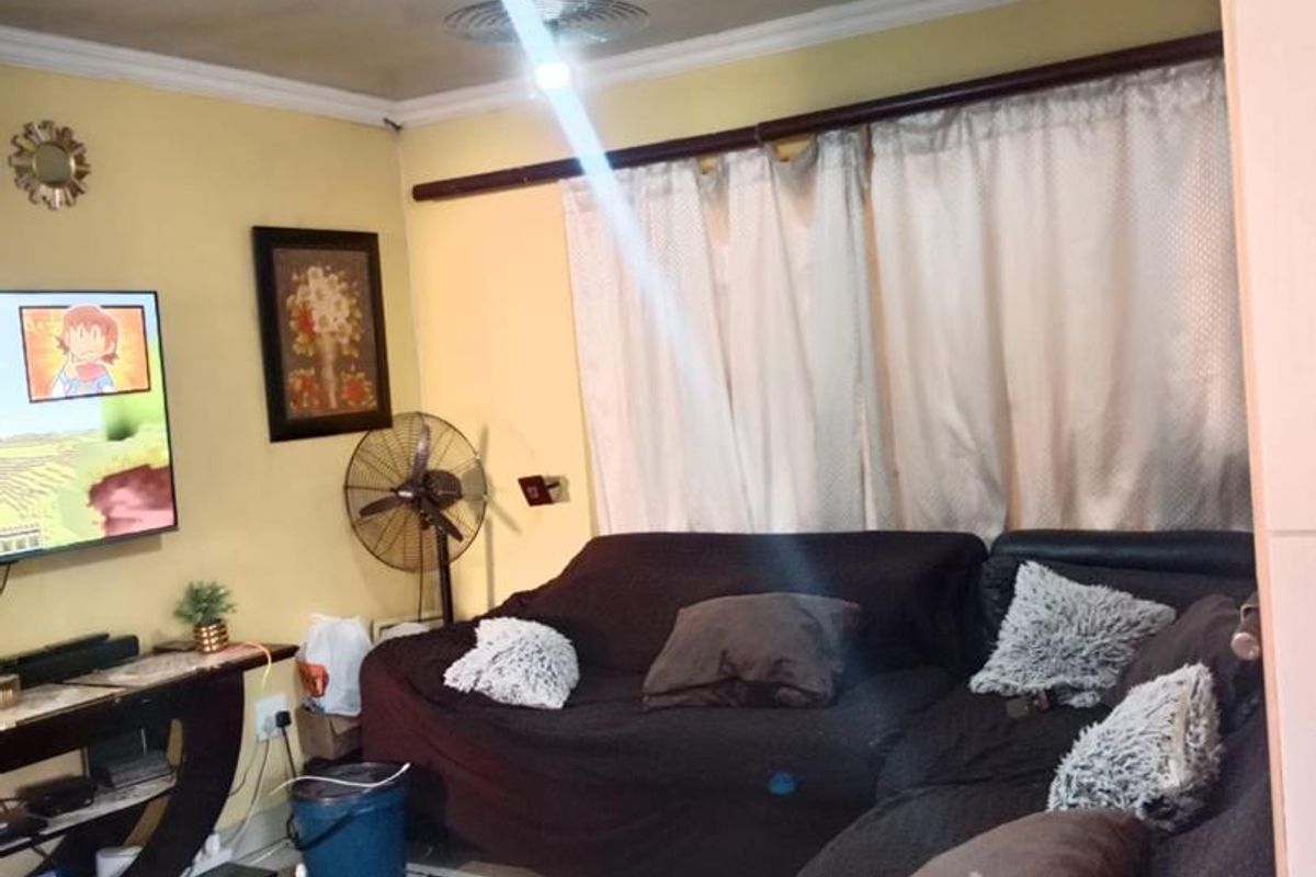 A living room featuring tiled flooring and ceiling cornice, currently requiring cosmetic updates to the wall finishes and ceiling.