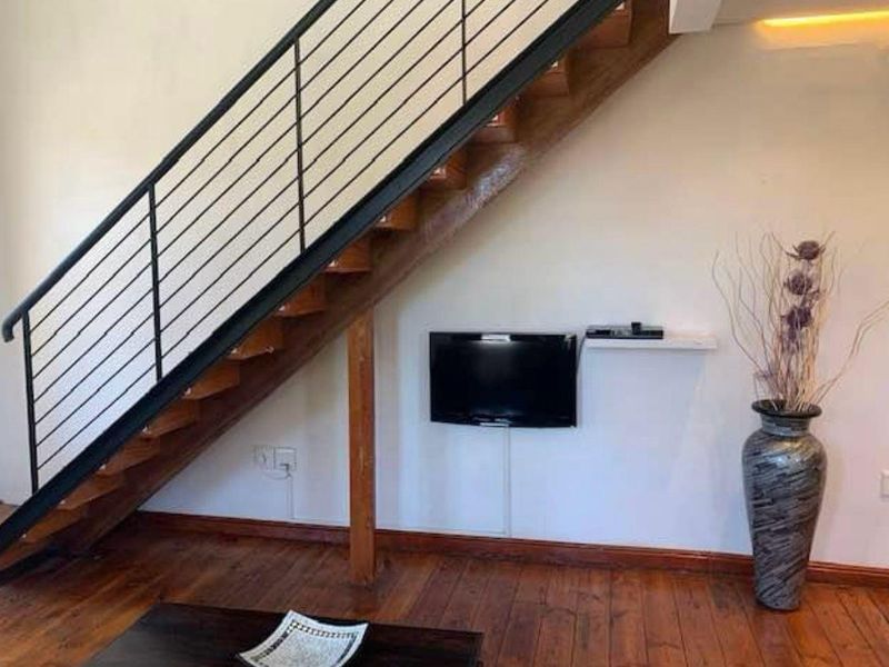 A living area featuring a timber staircase with a modern metal balustrade and polished hardwood flooring.