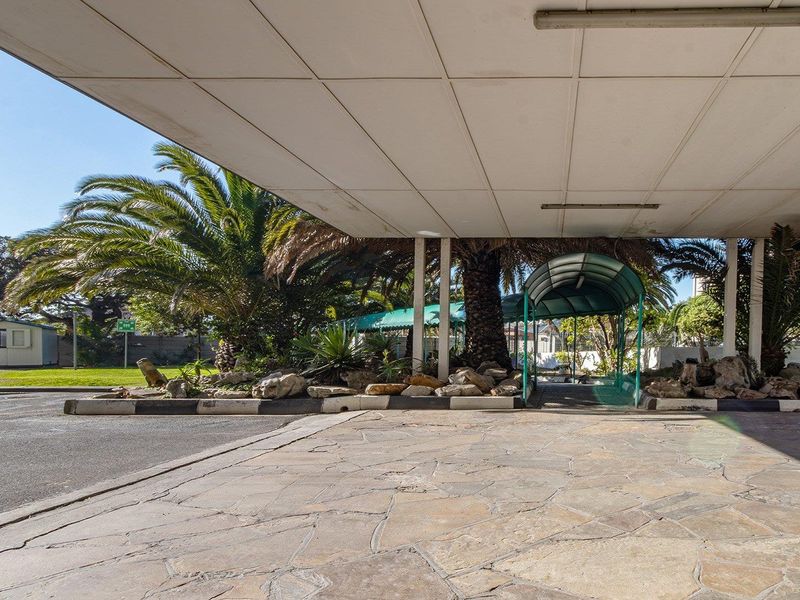 A covered entrance area featuring paved stone flooring and a structural canopy, providing a sheltered approach to the property.