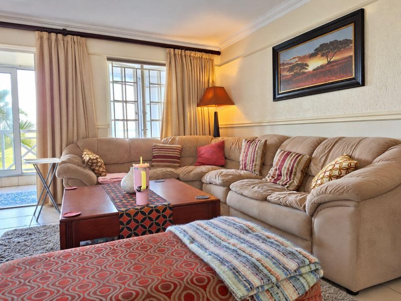 A comfortable living room featuring tiled flooring, crown molding, and direct access to an outdoor balcony through sliding glass doors.