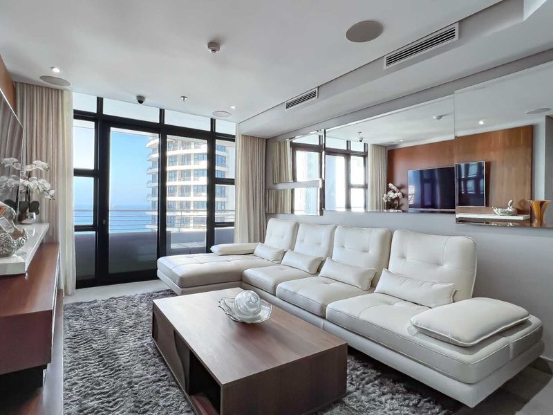 A modern living room featuring floor-to-ceiling windows, integrated ceiling speakers, ducted air conditioning, and a large wall-mounted mirror.