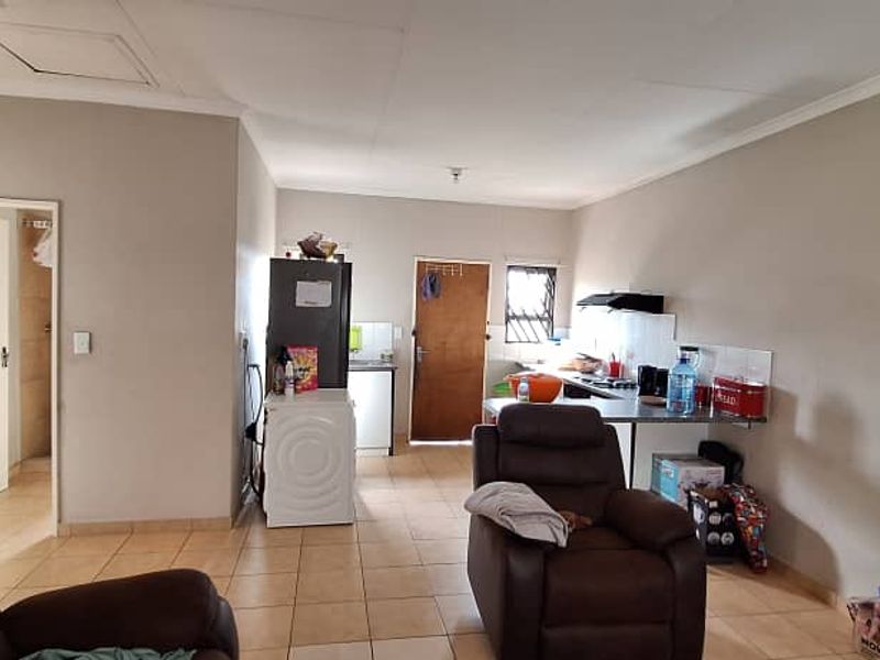 Open plan living area featuring tiled flooring and a functional kitchen space with built-in counter and extractor fan.