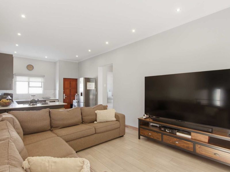 Open-plan living area featuring a modern kitchen with stone countertops, subway tile backsplash, gas hob, and recessed downlights throughout the space.