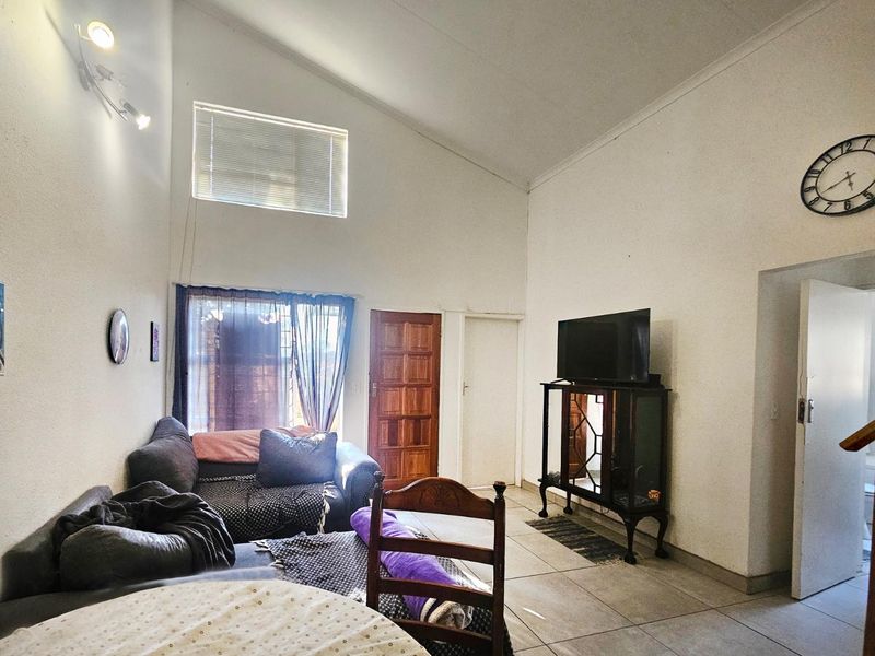 Spacious living room featuring a high vaulted ceiling, tiled flooring, and a large clerestory window that provides ample natural light.