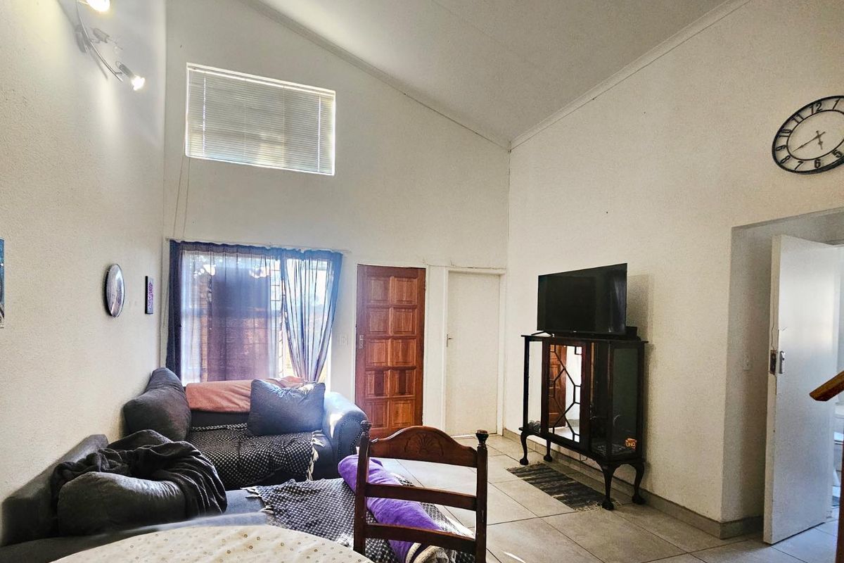 Spacious living room featuring a high vaulted ceiling, tiled flooring, and a large clerestory window that provides ample natural light.