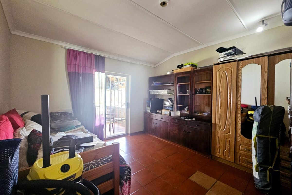 A bedroom featuring tiled flooring, built-in wooden cabinetry, and a sliding glass door providing access to an outdoor patio area.