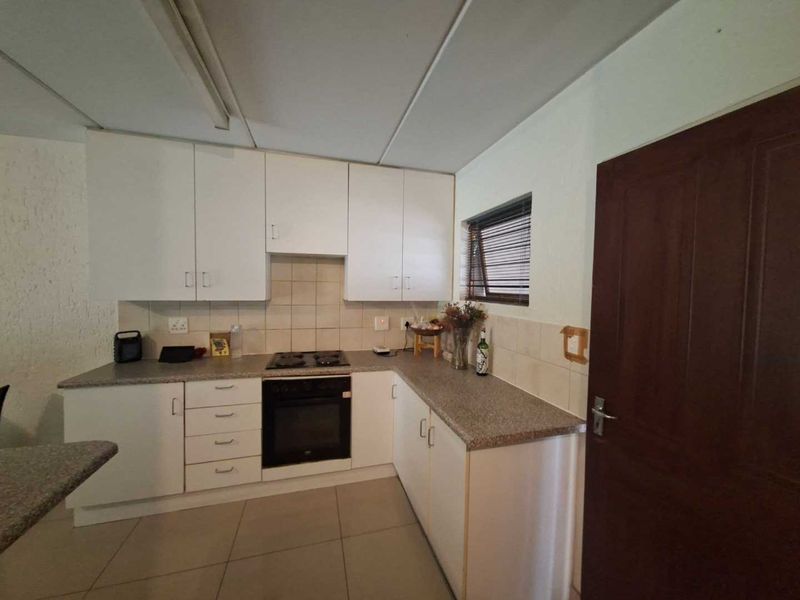 A functional kitchen featuring white cabinetry, a built-in oven and hob, stone-look countertops, and tiled flooring.