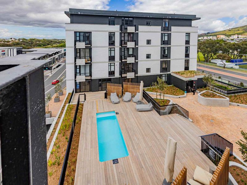 Elevated view of a modern apartment complex featuring a swimming pool, timber decking, and landscaped outdoor communal areas.