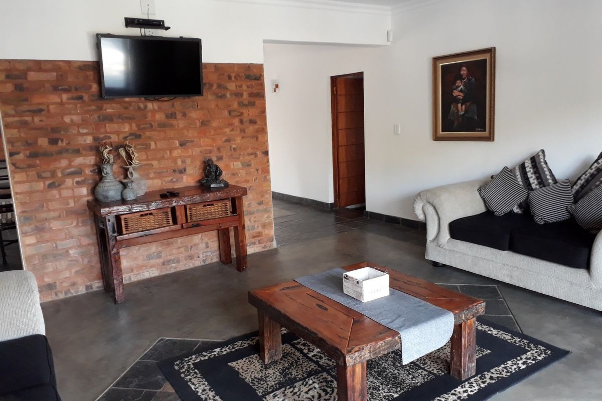 A living room featuring a rustic exposed brick feature wall, polished concrete flooring, and a wooden door leading to an adjacent hallway.
